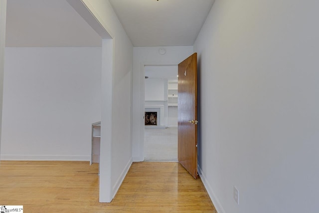 corridor featuring baseboards and light wood-style floors