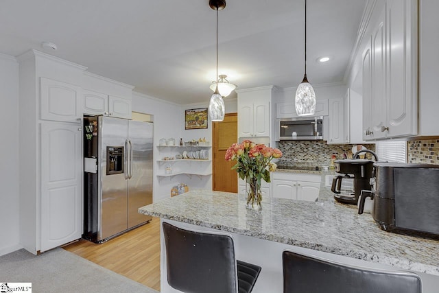 kitchen featuring decorative backsplash, white cabinets, stainless steel appliances, and a peninsula