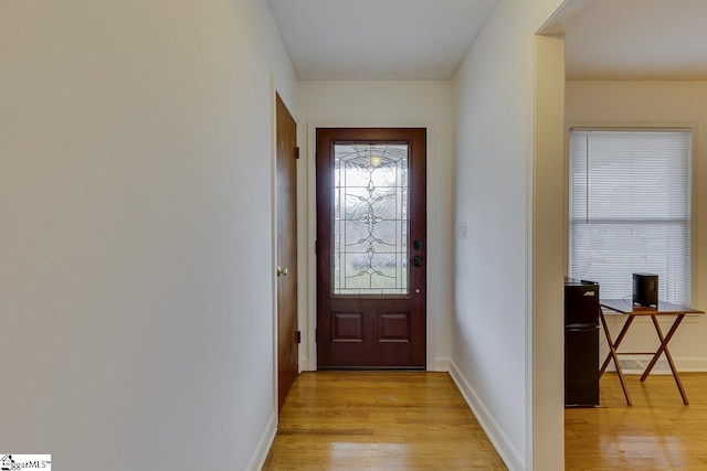doorway with baseboards and light wood-style flooring
