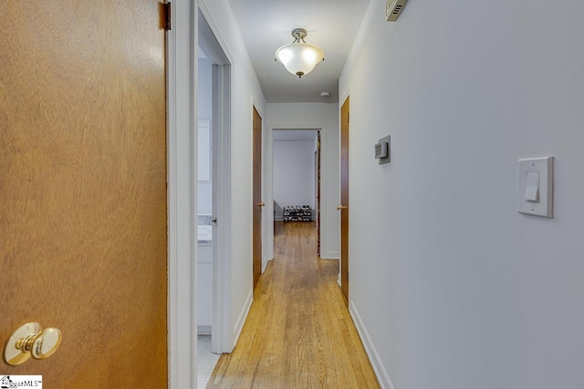 hallway with baseboards and light wood-style flooring
