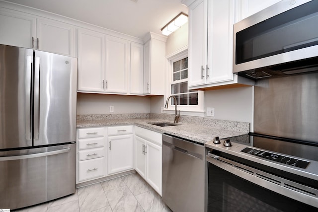 kitchen with white cabinets, marble finish floor, a sink, and appliances with stainless steel finishes