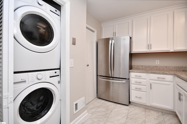 laundry area featuring marble finish floor, visible vents, stacked washer / dryer, and laundry area