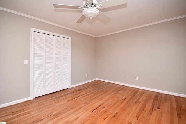 unfurnished bedroom featuring baseboards, light wood-type flooring, crown molding, and a closet