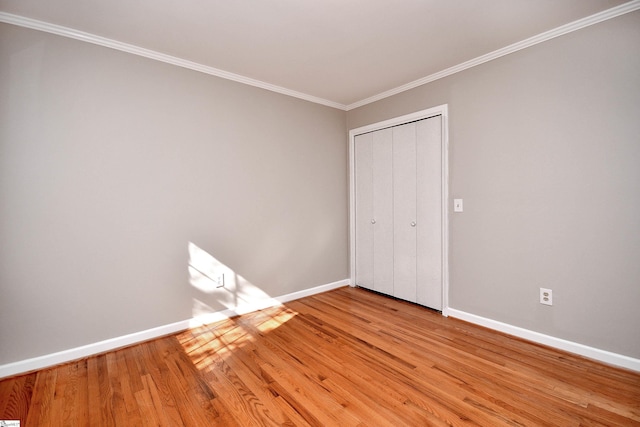 unfurnished bedroom with baseboards, a closet, light wood-style flooring, and ornamental molding