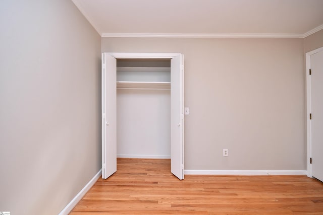 unfurnished bedroom with a closet, crown molding, light wood-style floors, and baseboards