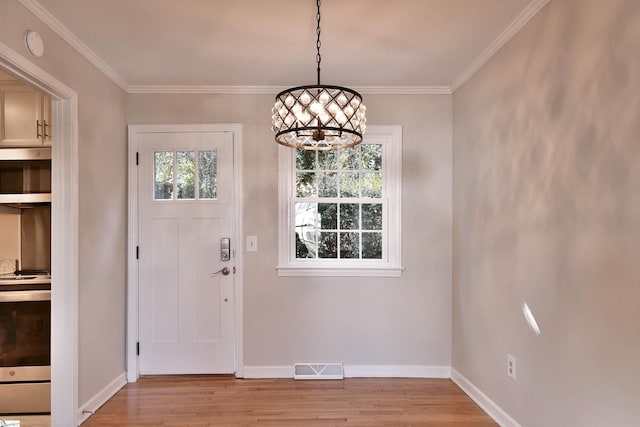 foyer entrance with light wood finished floors, baseboards, visible vents, and crown molding