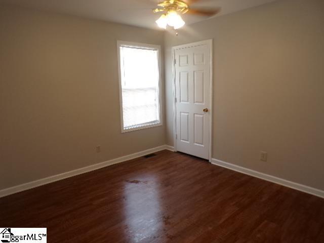unfurnished room with baseboards, ceiling fan, and dark wood-type flooring