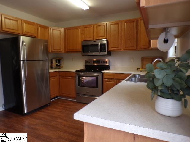 kitchen with light countertops, dark wood-style flooring, and appliances with stainless steel finishes