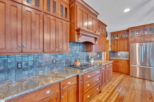 511 Palmer Way, Sunset, SC 29685 - kitchen with premium range hood, light wood-style floors, light stone countertops, appliances with stainless steel finishes, and brown cabinets