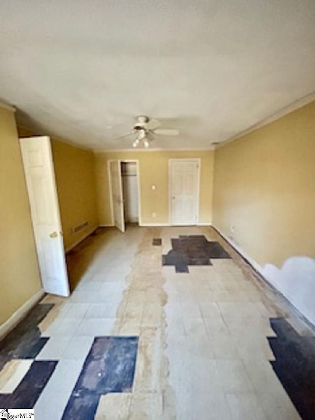 empty room featuring crown molding, baseboards, and ceiling fan