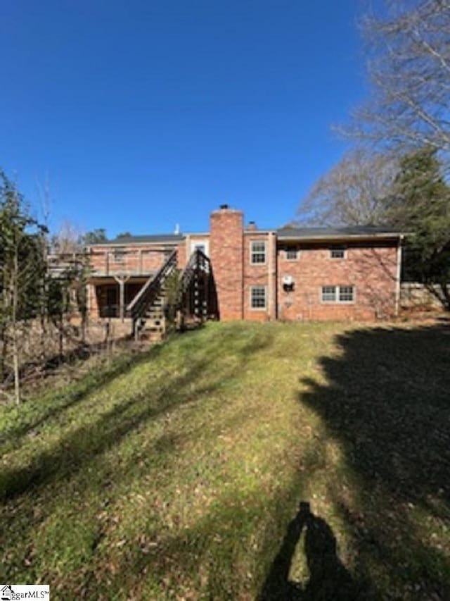 back of house featuring stairway and a yard