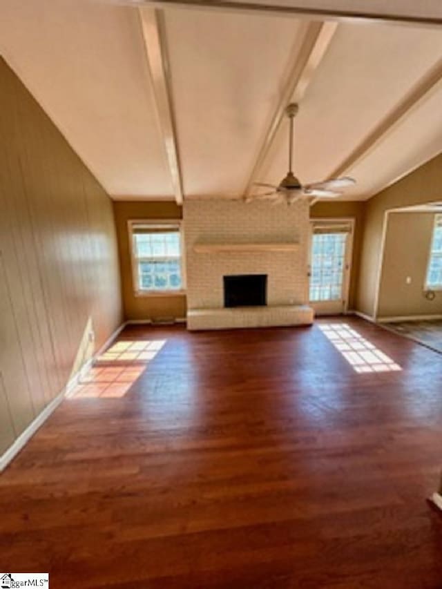 unfurnished living room featuring plenty of natural light, a fireplace, wood finished floors, and a ceiling fan