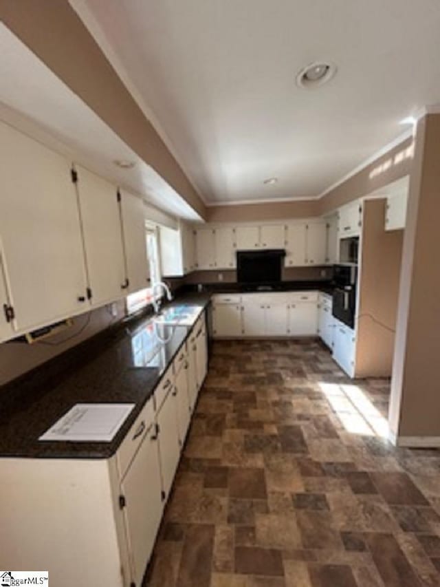 kitchen featuring stone finish floor, a sink, dark countertops, and oven