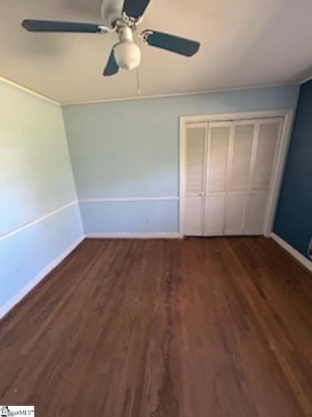 unfurnished bedroom with baseboards, wood finished floors, and a closet