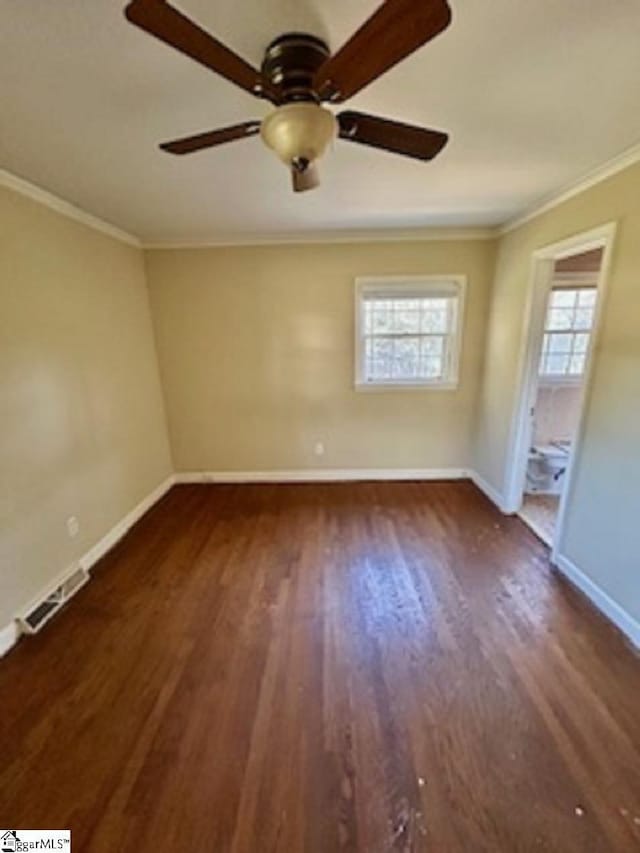 unfurnished bedroom featuring wood finished floors, ensuite bath, baseboards, visible vents, and ornamental molding