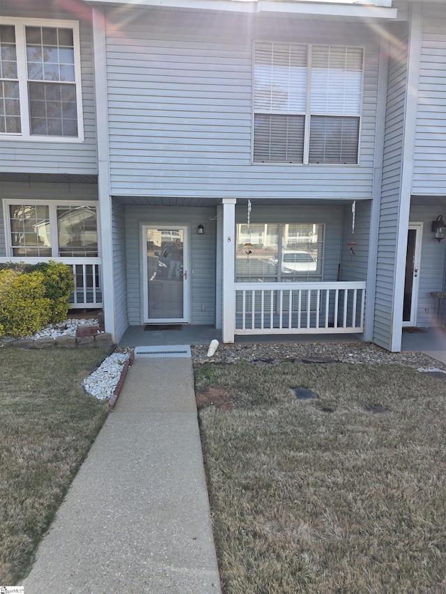 view of exterior entry featuring a lawn