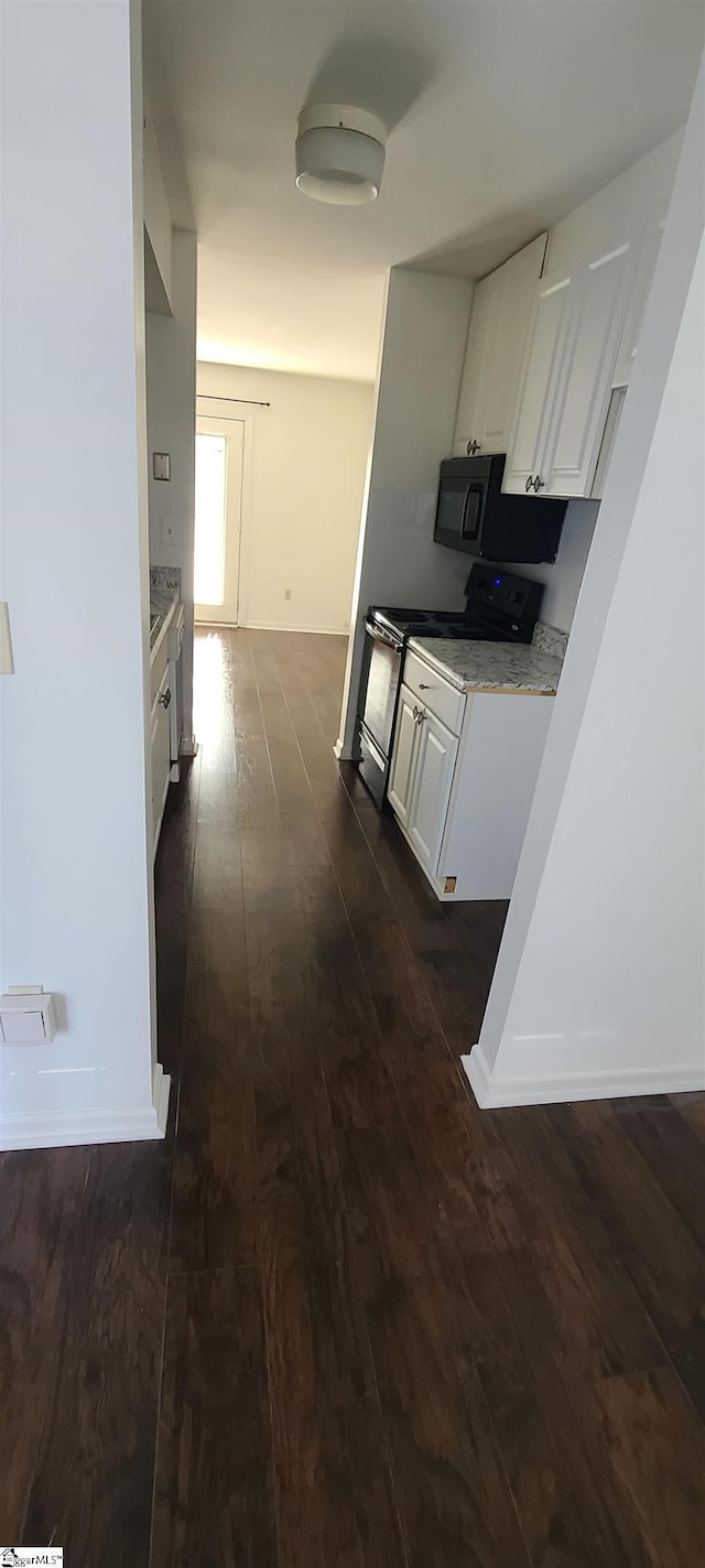 hall with dark wood-style floors and baseboards