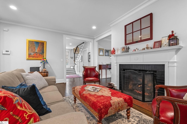 living room with a fireplace, crown molding, wood finished floors, and stairway