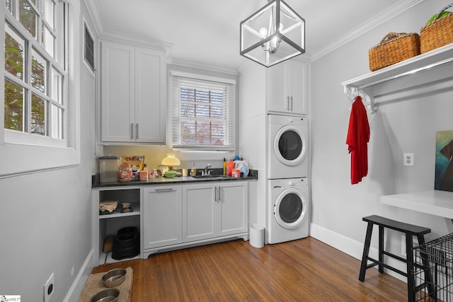 laundry area with crown molding, a sink, stacked washer / dryer, cabinet space, and dark wood-type flooring