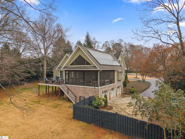 exterior space with stairway, solar panels, a sunroom, fence private yard, and a garage