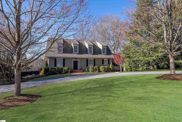 cape cod home with curved driveway and a front lawn