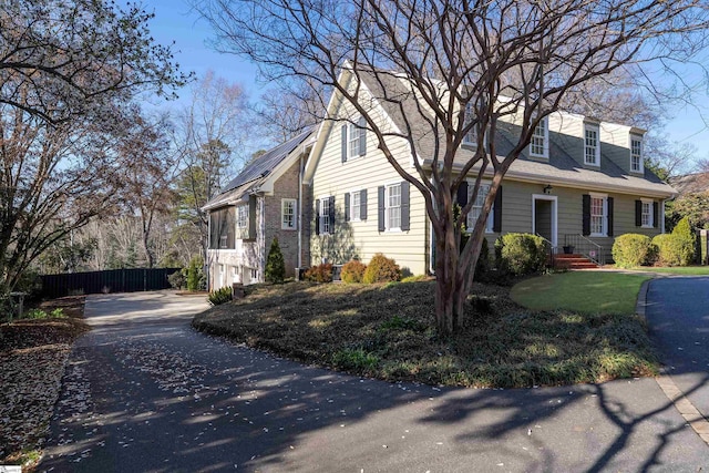 view of side of home with aphalt driveway and fence