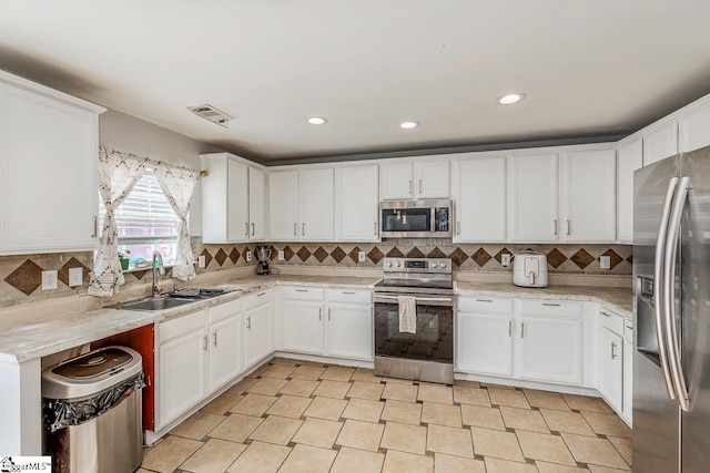 kitchen with a sink, tasteful backsplash, stainless steel appliances, visible vents, and white cabinets
