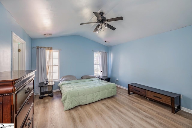 bedroom featuring baseboards, visible vents, wood finished floors, and lofted ceiling