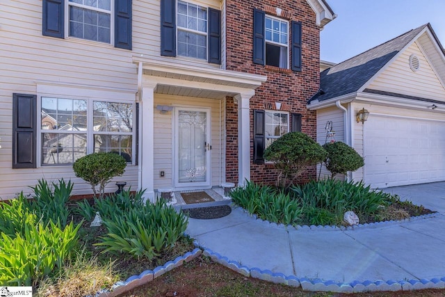 entrance to property with brick siding, concrete driveway, and an attached garage