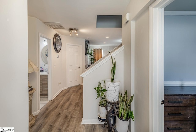 hallway featuring stairs, a sink, wood finished floors, baseboards, and visible vents