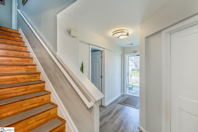 stairs with baseboards, visible vents, and wood finished floors