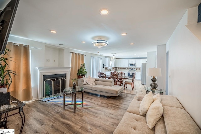 living room featuring a fireplace, light wood finished floors, and recessed lighting