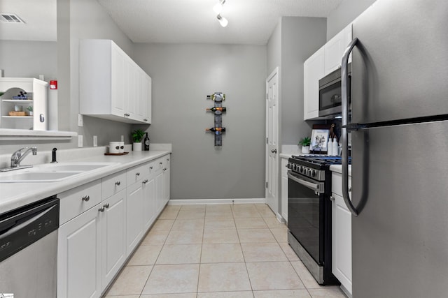 kitchen with white cabinetry, a sink, light tile patterned flooring, visible vents, and appliances with stainless steel finishes