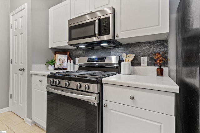kitchen featuring white cabinetry, backsplash, appliances with stainless steel finishes, and light tile patterned floors
