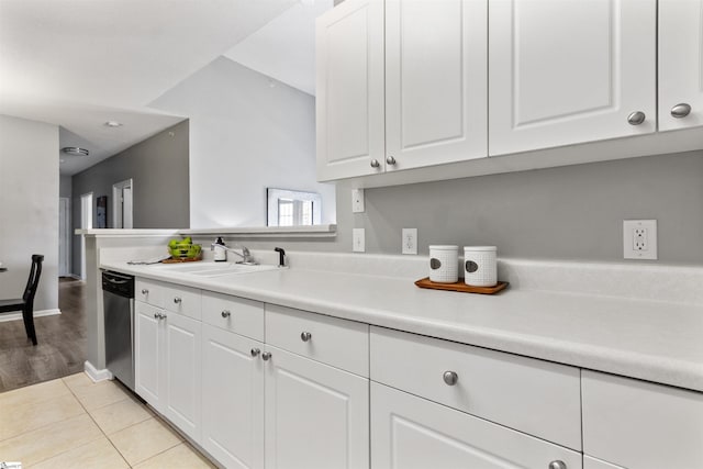 kitchen featuring light countertops, a sink, dishwasher, light tile patterned floors, and white cabinets