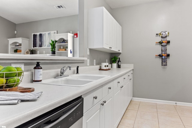 kitchen featuring light tile patterned flooring, light countertops, a sink, stainless steel dishwasher, and white cabinets