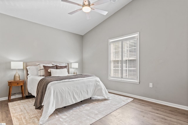 bedroom featuring baseboards, lofted ceiling, wood finished floors, and a ceiling fan