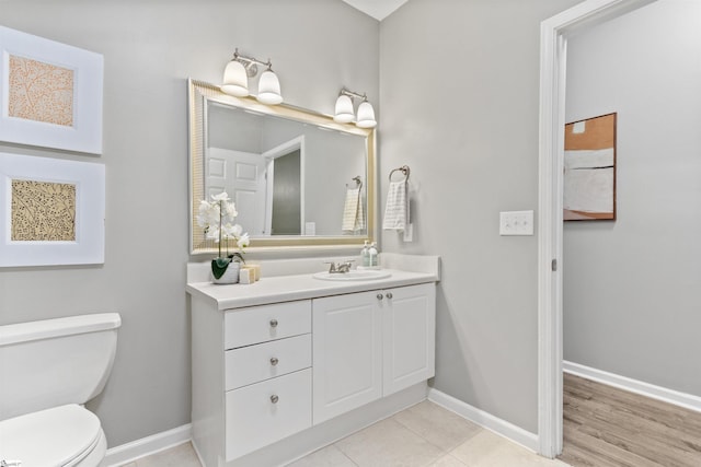 bathroom with toilet, vanity, and baseboards