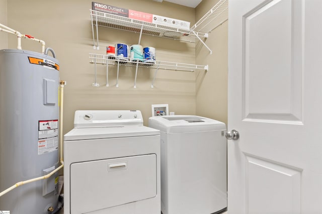 clothes washing area featuring water heater, washing machine and dryer, and laundry area