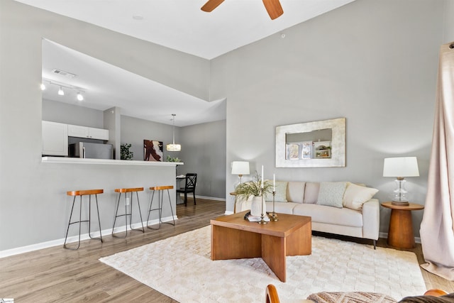 living room featuring baseboards, ceiling fan, visible vents, and light wood-style floors