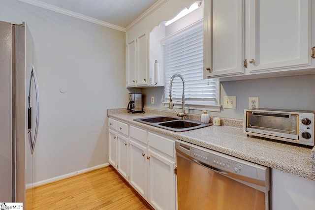 kitchen with a sink, white cabinetry, stainless steel appliances, a toaster, and ornamental molding