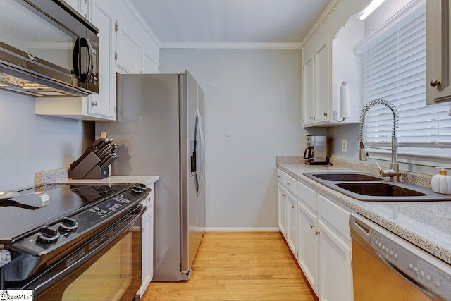 kitchen with white cabinets, light wood-style flooring, ornamental molding, a sink, and black appliances