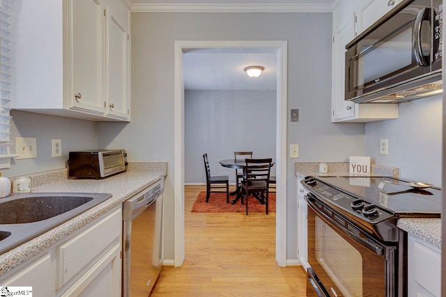 kitchen featuring light countertops, light wood-type flooring, a toaster, white cabinets, and black appliances