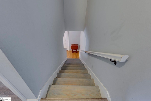 staircase with baseboards and wood finished floors
