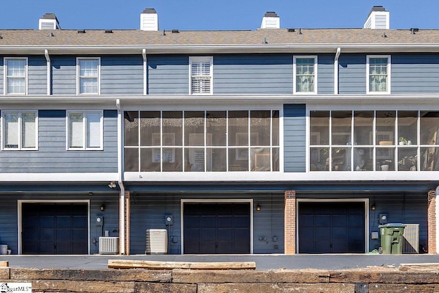 back of property featuring a sunroom, central AC unit, and a chimney
