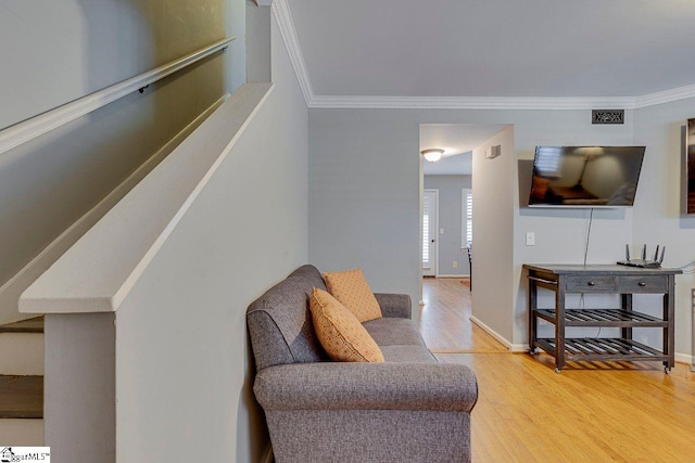 living area with baseboards, crown molding, and light wood-type flooring