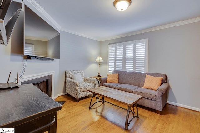 living room with baseboards, a fireplace, crown molding, and light wood-style floors