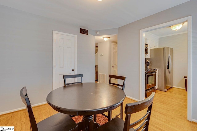 dining space with baseboards, visible vents, and light wood-style flooring