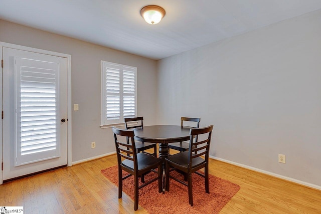 dining space with baseboards and light wood-type flooring