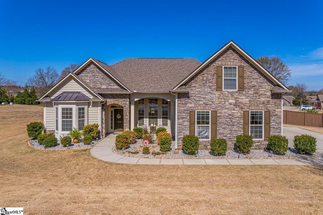105 Cooper Oaks Ct, Simpsonville, SC 29681 - view of front facade with stone siding, metal roof, fence, a front yard, and a standing seam roof